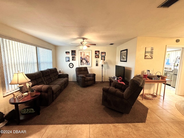 tiled living area featuring visible vents, a ceiling fan, and carpet flooring