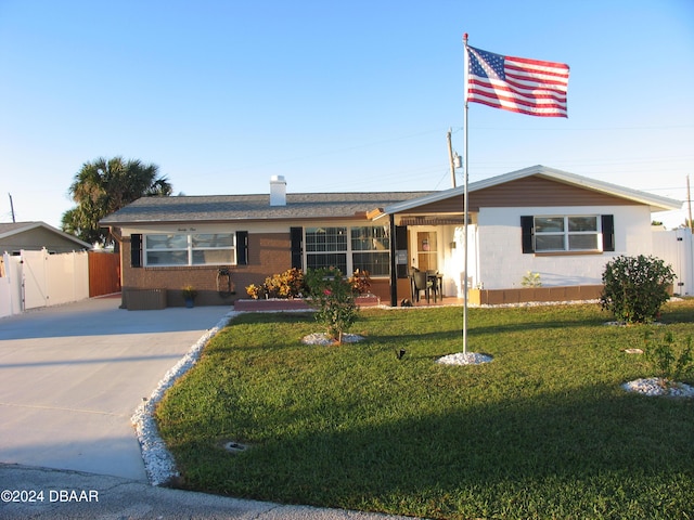 ranch-style house featuring fence, concrete driveway, and a front yard