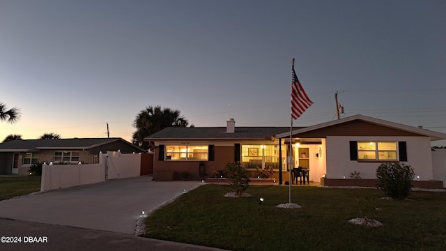 ranch-style house with stucco siding, fence, concrete driveway, and a front yard