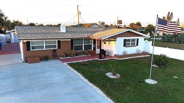 single story home featuring a shingled roof, a front yard, brick siding, and fence