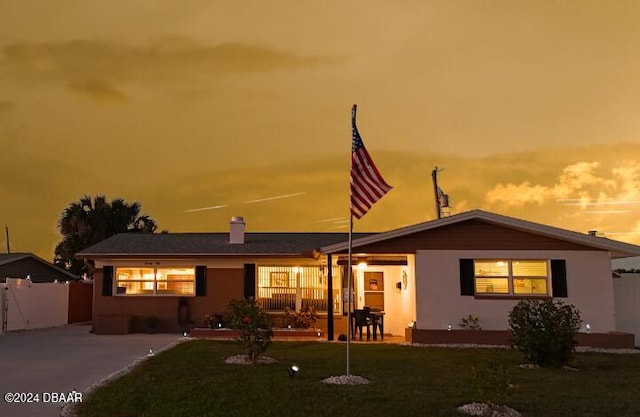 view of front of house with a lawn, a patio area, fence, and stucco siding