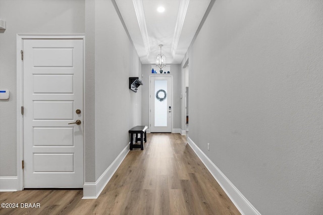 entryway featuring a chandelier, hardwood / wood-style flooring, and crown molding