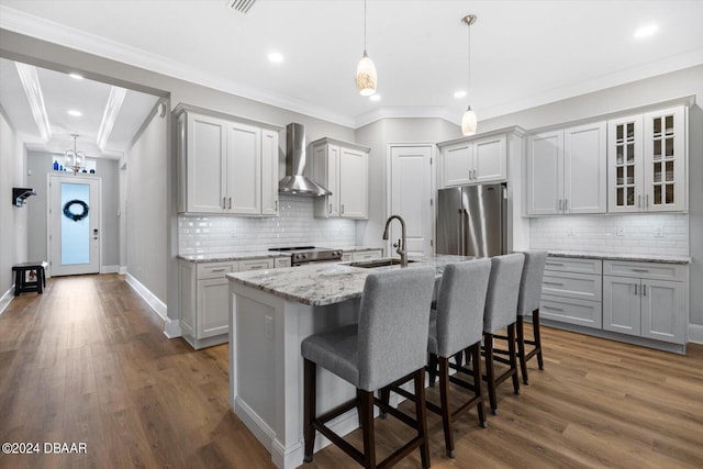 kitchen featuring stainless steel appliances, sink, a kitchen island with sink, dark wood-type flooring, and wall chimney range hood