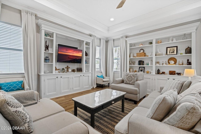 living room featuring built in shelves, ceiling fan, crown molding, and light hardwood / wood-style flooring