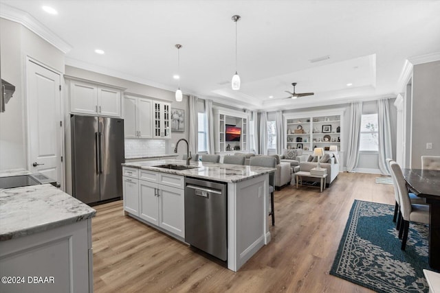 kitchen with hardwood / wood-style flooring, white cabinetry, appliances with stainless steel finishes, a kitchen island with sink, and pendant lighting