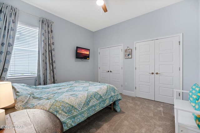 carpeted bedroom with multiple closets, multiple windows, and ceiling fan