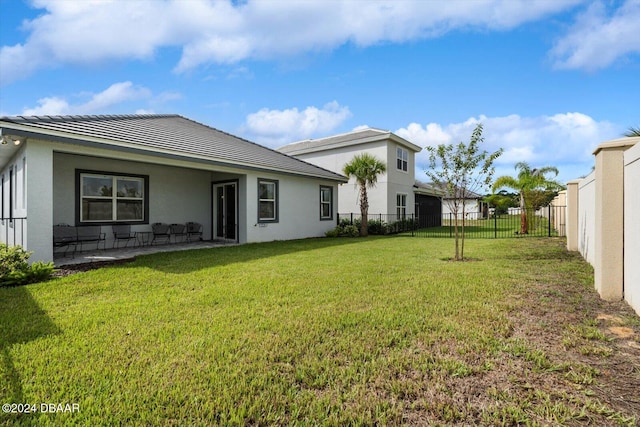 rear view of house featuring a lawn and a patio