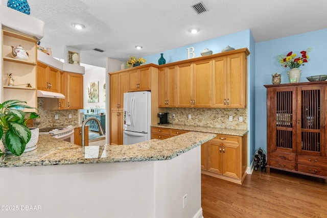 kitchen featuring visible vents, light stone countertops, wood finished floors, white appliances, and open shelves