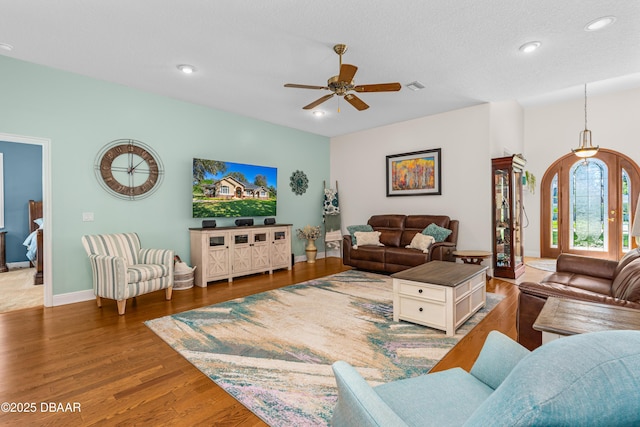 living room featuring a ceiling fan, wood finished floors, visible vents, baseboards, and recessed lighting