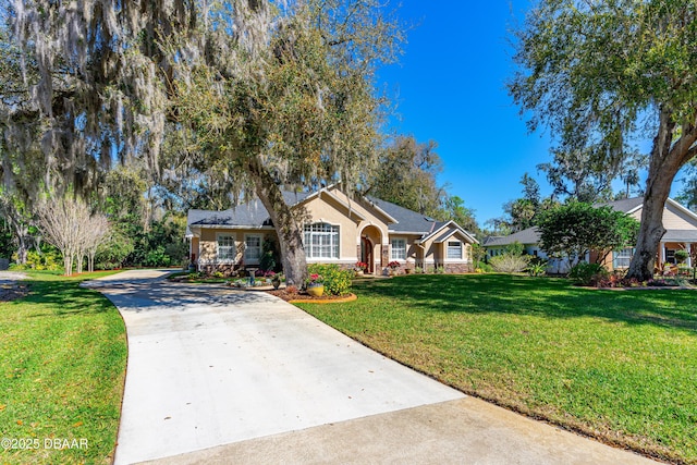 ranch-style home with a front yard, stone siding, driveway, and stucco siding