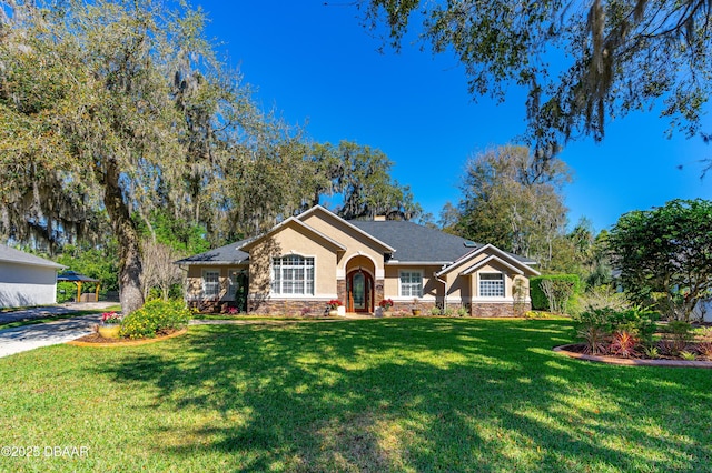 ranch-style house with stucco siding, stone siding, and a front lawn