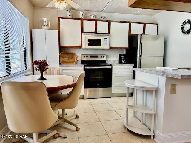 kitchen featuring light tile patterned flooring, appliances with stainless steel finishes, white cabinets, and ceiling fan