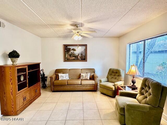 living room with ceiling fan, a textured ceiling, and light tile patterned floors