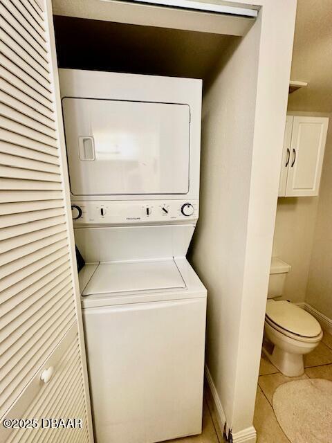 laundry room with stacked washing maching and dryer and light tile patterned floors