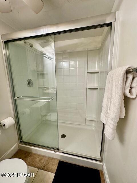 bathroom featuring tile patterned flooring, a shower with shower door, and toilet