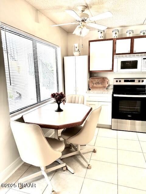 kitchen featuring stainless steel electric range oven, light tile patterned floors, white cabinets, and a textured ceiling