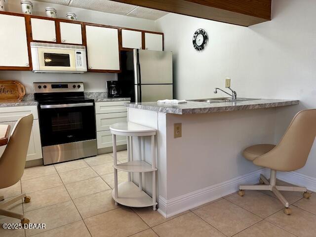 kitchen with stainless steel appliances, sink, a breakfast bar area, and white cabinets