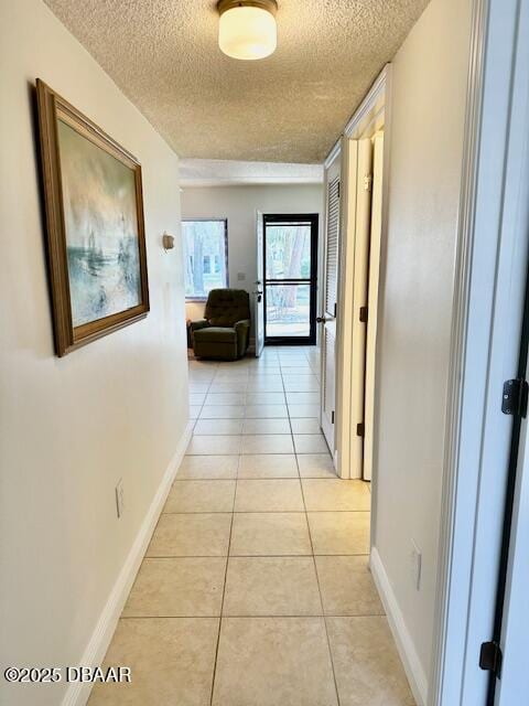 corridor featuring light tile patterned flooring and a textured ceiling