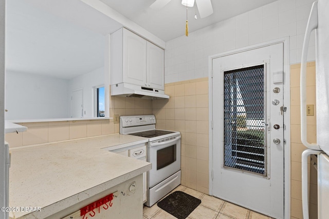 kitchen featuring under cabinet range hood, white appliances, tile walls, white cabinetry, and light countertops