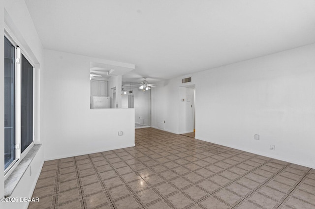 spare room with a ceiling fan, visible vents, and baseboards