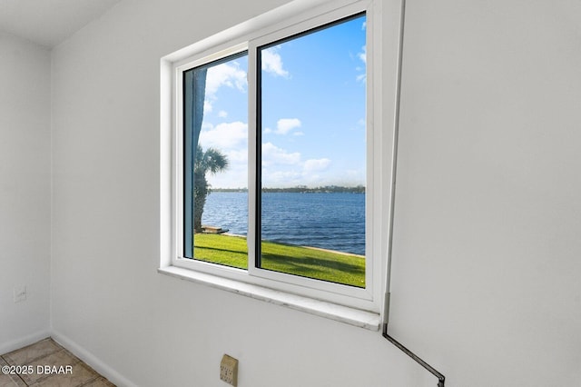 tiled spare room with a water view and baseboards