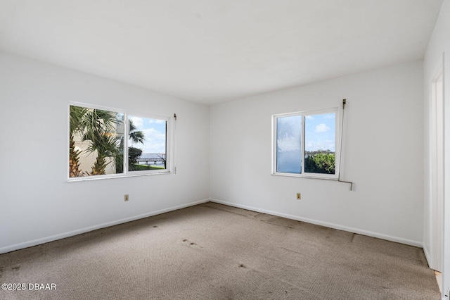 unfurnished room with carpet floors, a healthy amount of sunlight, and baseboards