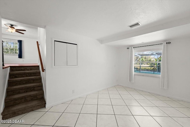 unfurnished room with stairway, plenty of natural light, a ceiling fan, and visible vents