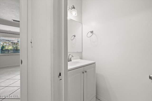 bathroom with tile patterned floors, a textured ceiling, vanity, and baseboards