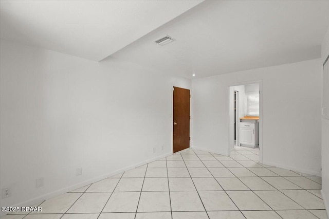 empty room featuring light tile patterned floors, visible vents, and baseboards