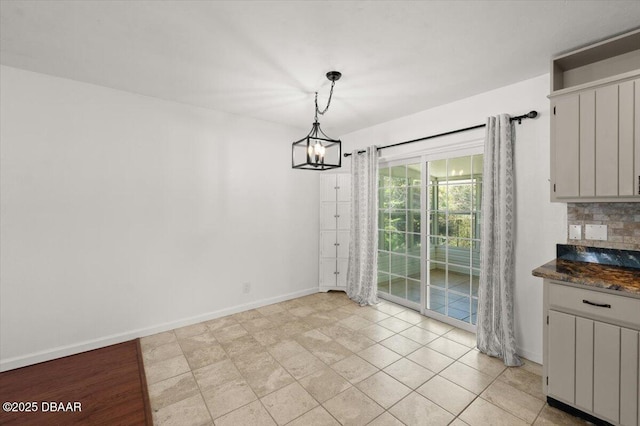 unfurnished dining area featuring a notable chandelier and baseboards