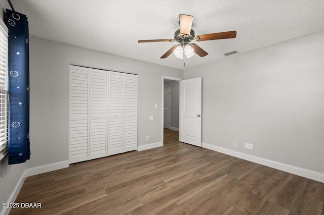 unfurnished bedroom featuring visible vents, a textured ceiling, baseboards, and wood finished floors