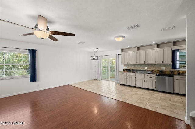 kitchen with dishwasher, dark countertops, light wood finished floors, and decorative backsplash