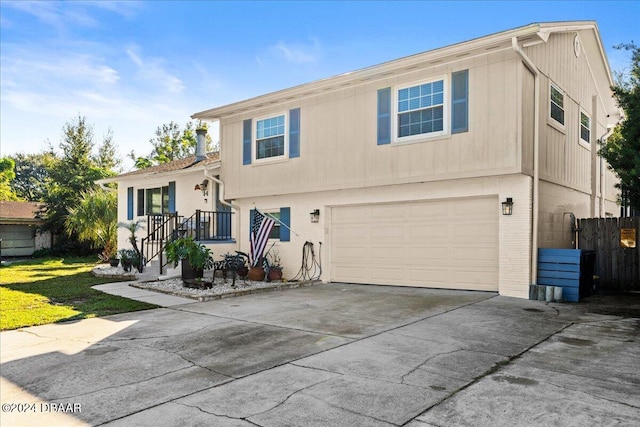 tri-level home with concrete driveway, an attached garage, fence, and brick siding