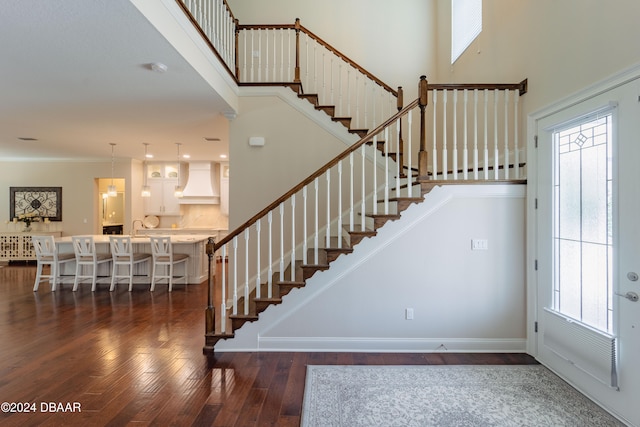 stairway with crown molding, hardwood / wood-style floors, and a towering ceiling