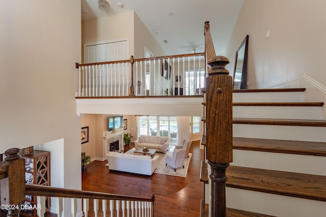 stairway with wood-type flooring, a towering ceiling, and ceiling fan