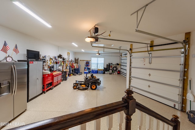 garage featuring a garage door opener and stainless steel refrigerator with ice dispenser