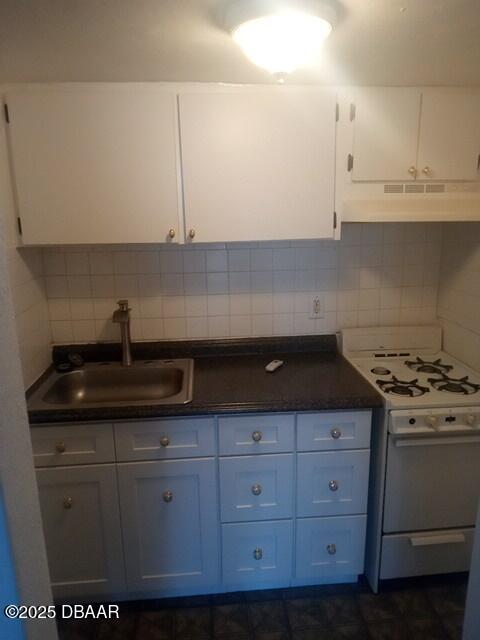 kitchen with tasteful backsplash, sink, white gas range oven, and white cabinets