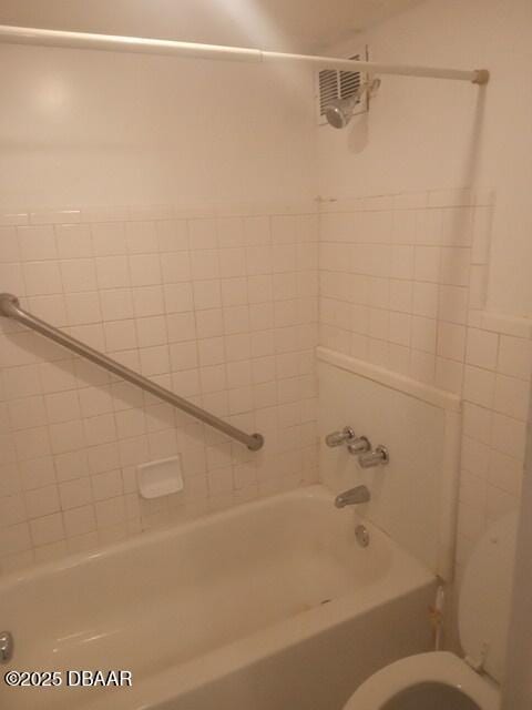 bathroom with tiled shower / bath combo and toilet