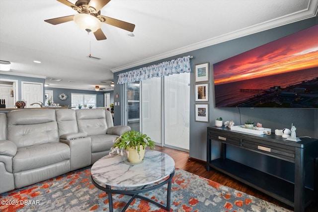 living room featuring ceiling fan, ornamental molding, and wood-type flooring