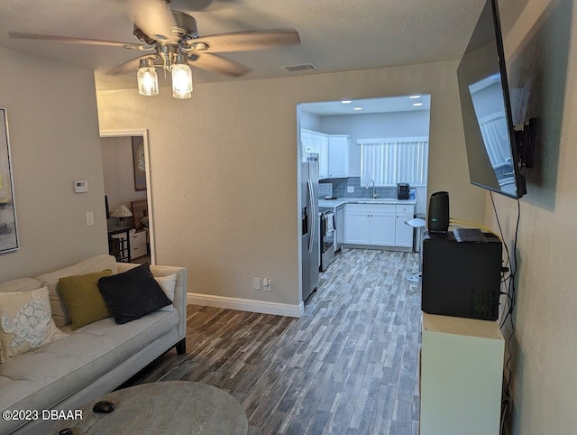 living room with dark hardwood / wood-style flooring, sink, and ceiling fan