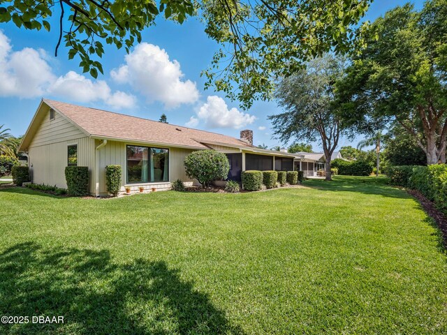 257 Sweet Bay Ave, New Smyrna Beach, FL 32168 - back of house featuring a chimney, a yard, and a sunroom