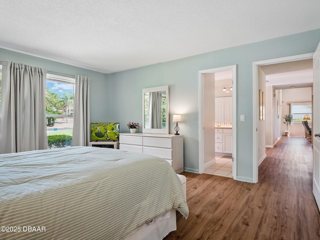 257 Sweet Bay Ave, New Smyrna Beach, FL 32168 - bedroom featuring light wood-type flooring, ensuite bathroom, baseboards, and a textured ceiling