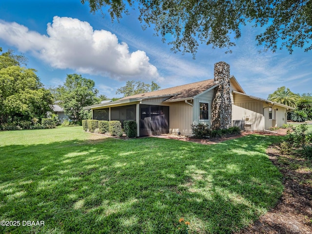 257 Sweet Bay Ave, New Smyrna Beach, FL 32168 - rear view of house featuring a sunroom, a lawn, a chimney, and board and batten siding