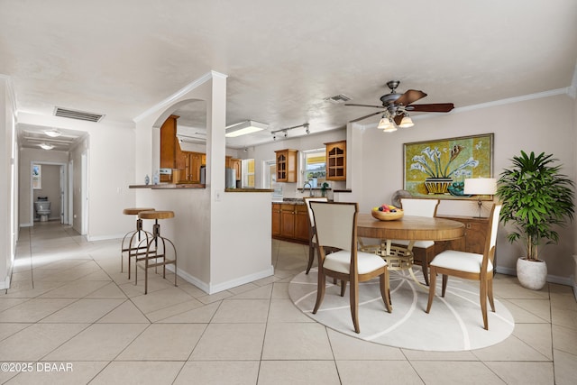 dining room featuring light tile patterned floors, a ceiling fan, baseboards, and ornamental molding