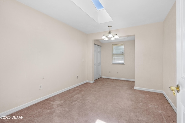 carpeted spare room featuring a skylight, a chandelier, and baseboards