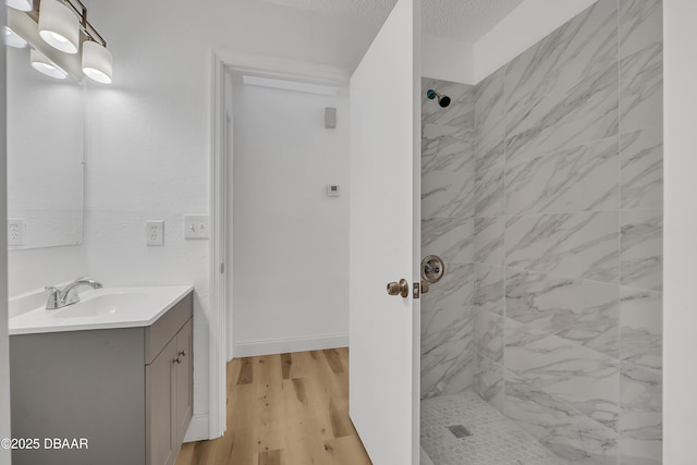 bathroom with tiled shower, a textured ceiling, vanity, and hardwood / wood-style flooring