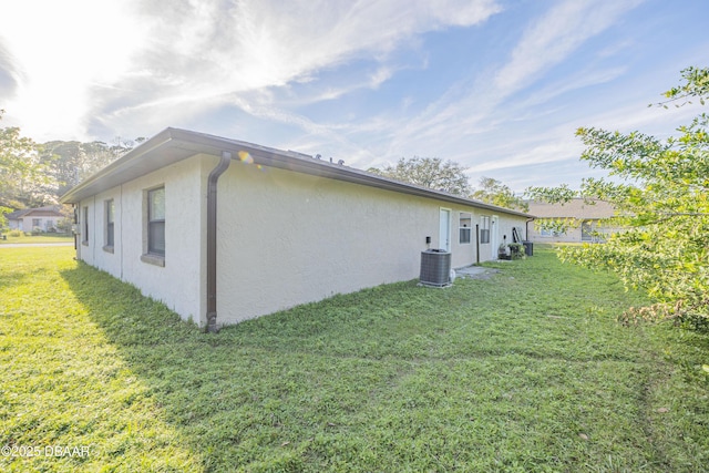 view of property exterior with central AC and a yard