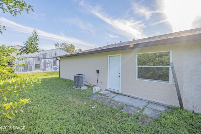 back of property with central air condition unit and a yard