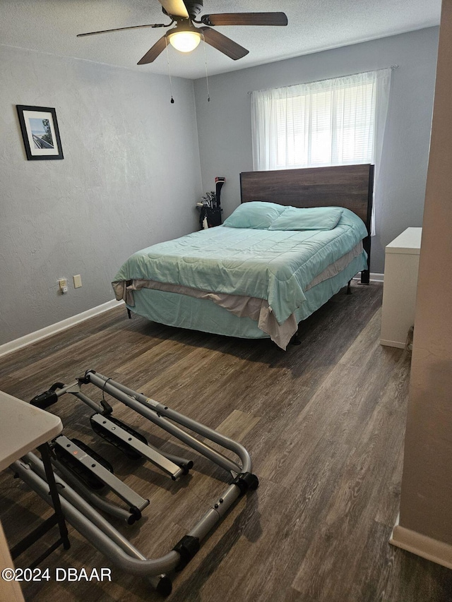 bedroom featuring ceiling fan, dark hardwood / wood-style floors, and a textured ceiling