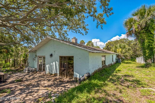 4519 Saxon Dr, New Smyrna Beach, FL 32169 - view of property exterior featuring stucco siding, a chimney, and french doors